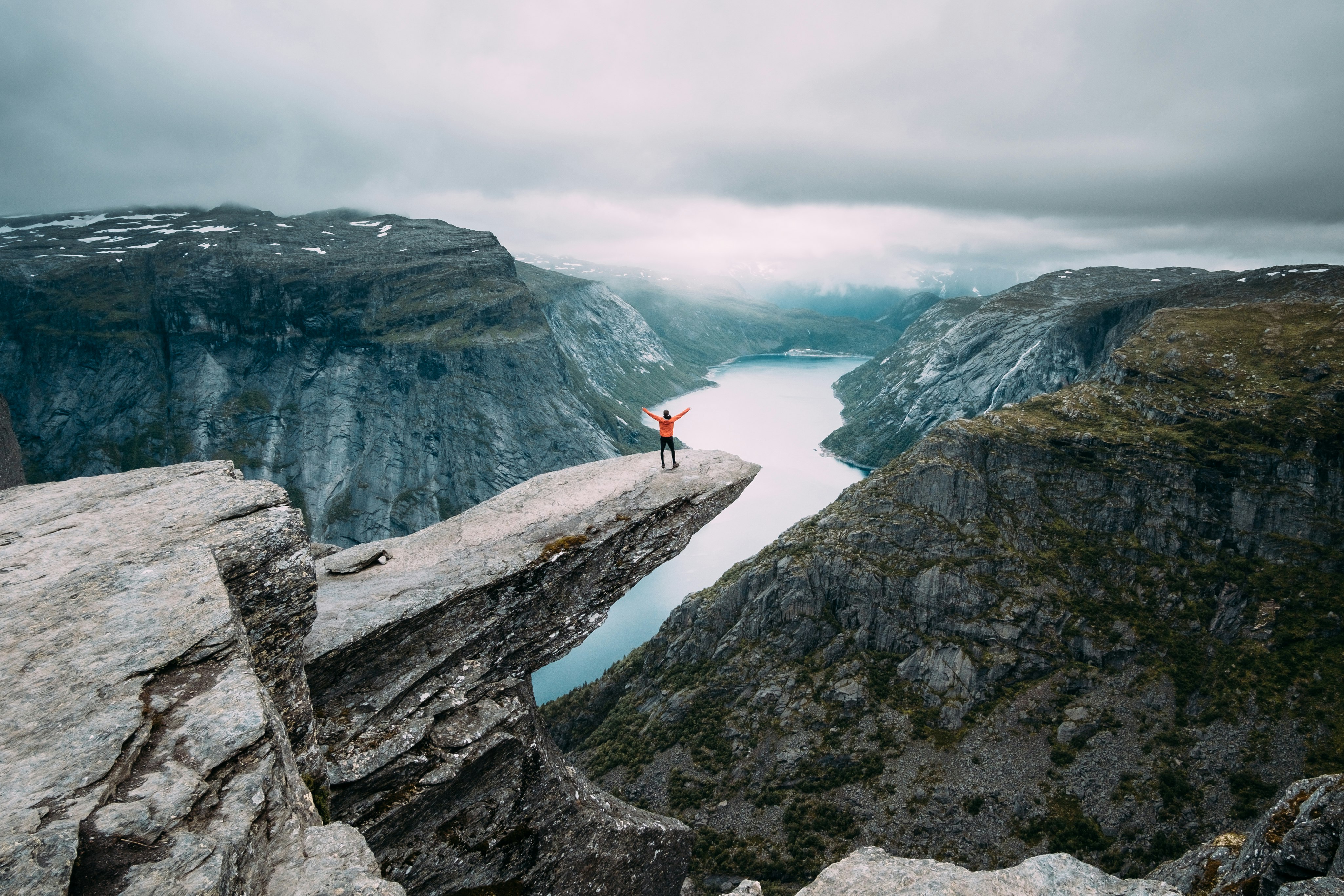 person standing on gray high-rise rock formation at daytime